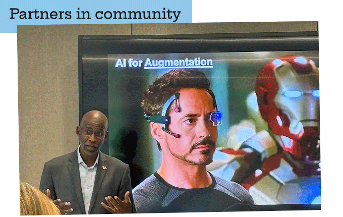 Dean Williamson presenting in front of a screen showing AI for Augmentation
