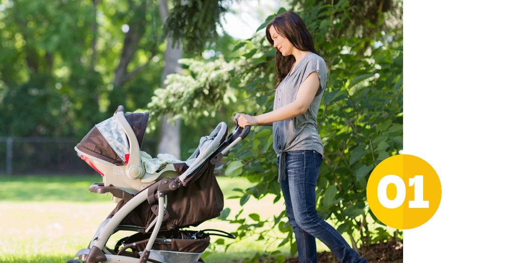 young mom walking with a baby stroller in a wooded area