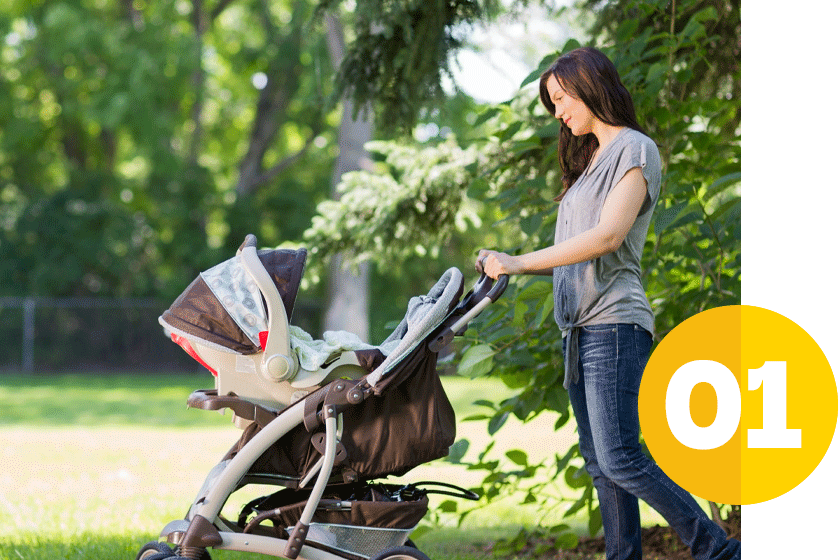 young mom walking with a baby stroller in a wooded area