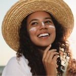 Person outdoors wearing sunhat and sunscreen on their nose and cheeks.