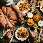 Close-up view of holiday table that includes pumpkins, pasta and wine.