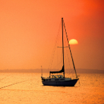 A sailboat with the sun in the background.