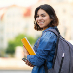 Smiling student with their backpack and notebook.